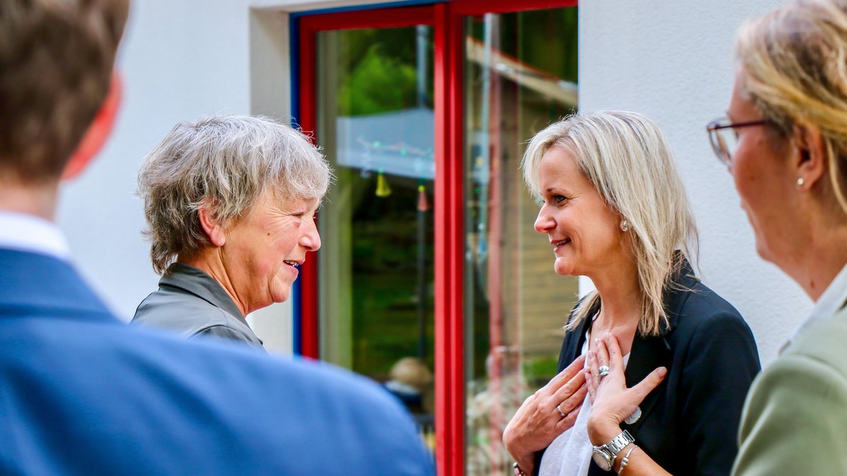 Landtagspräsidentin Hanna Naber spricht mit einer lächelnden blonden Dame. Im Vordergrund sind zwei weitere Personen zu sehen.