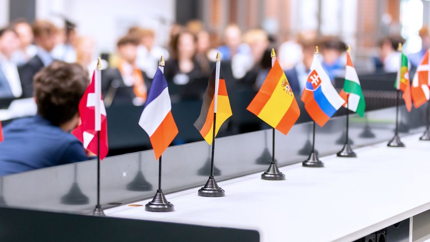Miniaturflaggen mehrerer EU-Mitgliedsstaaten im Forum des Niedersächsischen Landtages. Im Hintergrund sind unscharf die Mitglieder des jungen Europaparlamentes zu sehen.