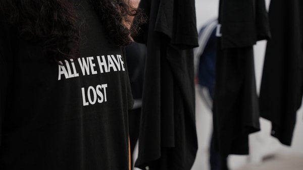 Nahaufnahme eines T-Shirts mit der Aufschrift 'ALL WE HAVE LOST', das von der Künstlerin Farzane Vaziritabar getragen wird