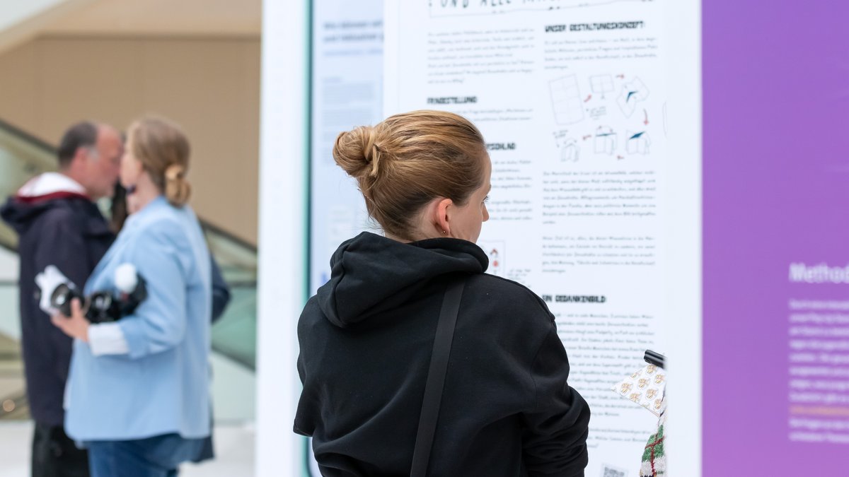 Eine Person steht vor bunten Ausstellungswänden.