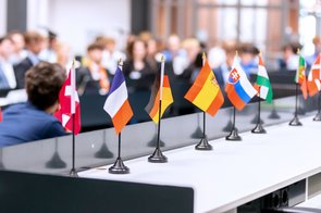 Bild: © Niedersächsischer Landtag Miniaturflaggen mehrerer EU-Mitgliedsstaaten im Forum des Niedersächsischen Landtages. Im Hintergrund sind unscharf die Mitglieder des jungen Europaparlamentes zu sehen.