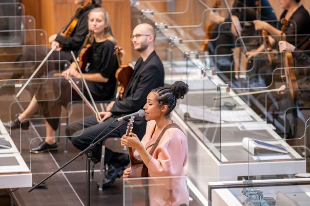 Bild: © Lea Schunk/Niedersächsischer Landtag Sängerin Tokunbo Akinro und das Orchester musizieren auf den eigentlichen Regierungsbänken