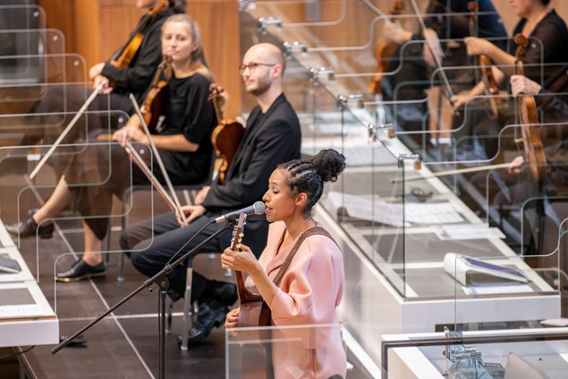 Sängerin Tokunbo Akinro und das Orchester musizieren auf den eigentlichen Regierungsbänken