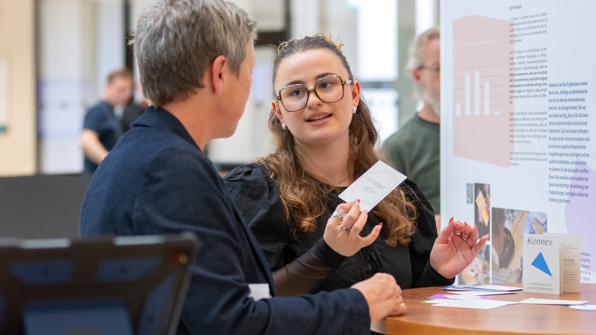 Landtagspräsidentin Hanna Naber im Gespräch mit einer Studentin vor der Ausstellungswand eines Projektes.