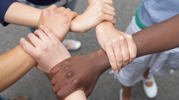 Menschen mit verschiedenen Hautfarben halten einander fest Klick öffnet die Seite: Kommission zu Fragen der Migration und Teilhabe