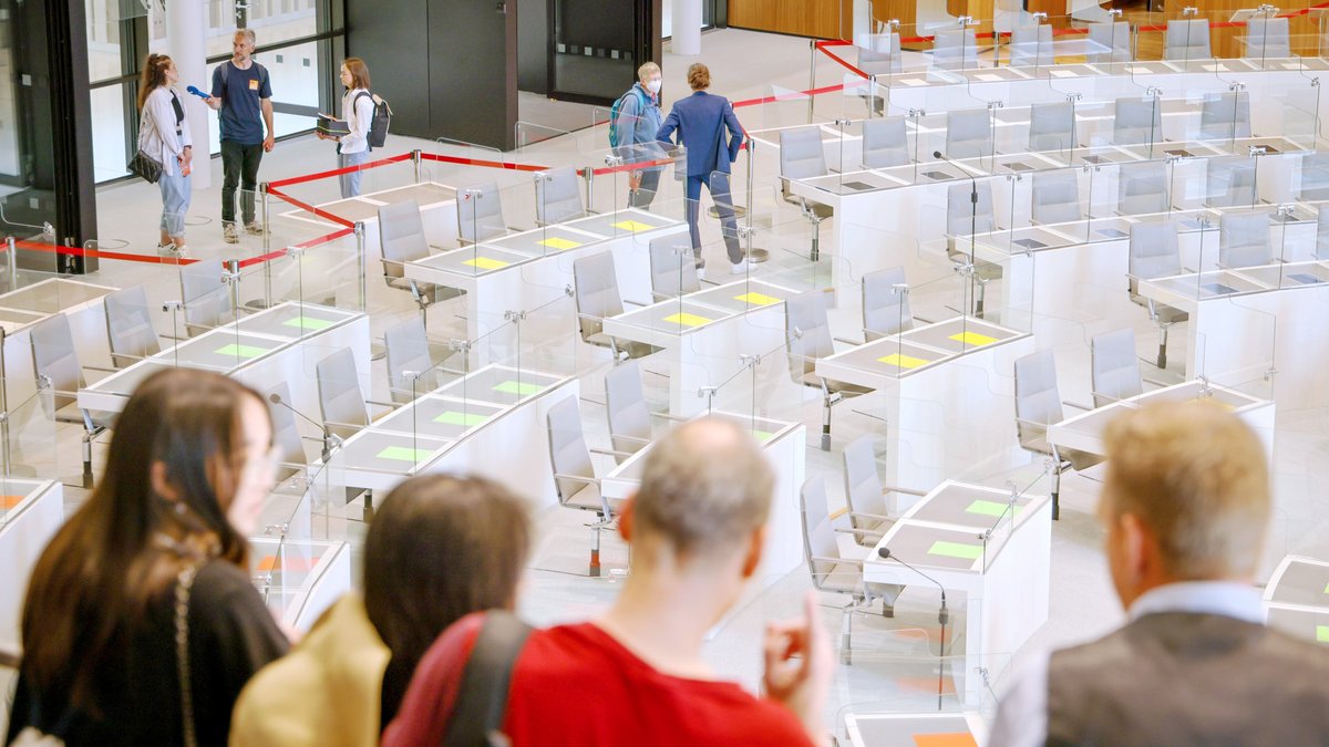 Gäste blicken von einer Tribüne in den Plenarsaal