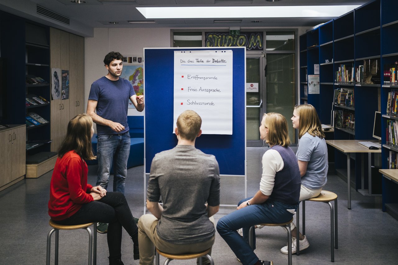 Bild: © Hertie-Stiftung/Jugend debattiert Schüler und Schülerinnen vor einem Flipchart.