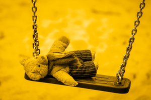 Stoffteddy liegend auf einer Schaukel