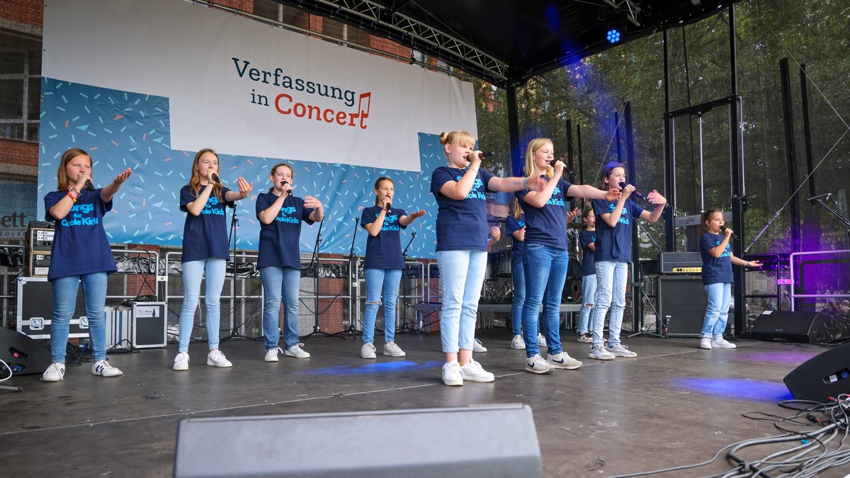 Eine junge Band singend und tanzend auf der Bühne.