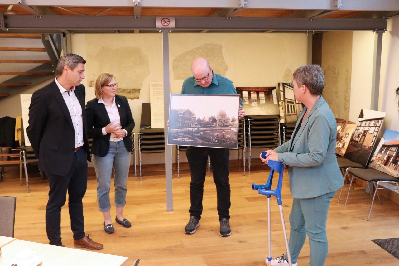 Landtagspräsidentin Naber während eines Besuchs der Synagoge Einbeck, ein Vertreter der Synagoge zeigt ein Bild; links zwei weitere Personen.