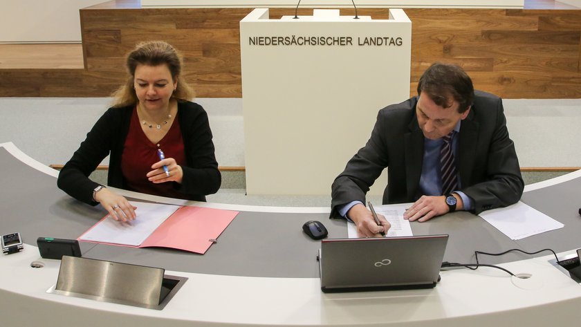 Eine Stenografin und ein Stenograf schreiben die Rede im Plenum mit.