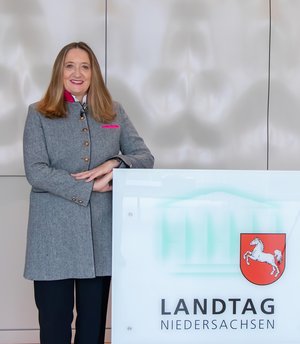 Bild: © Niedersächsischer Landtag Landtagespräsidentin Dr. Gabriele Andretta steht neben einem Rednerpult mit dem Logo des Niedersächsischen Landtages.