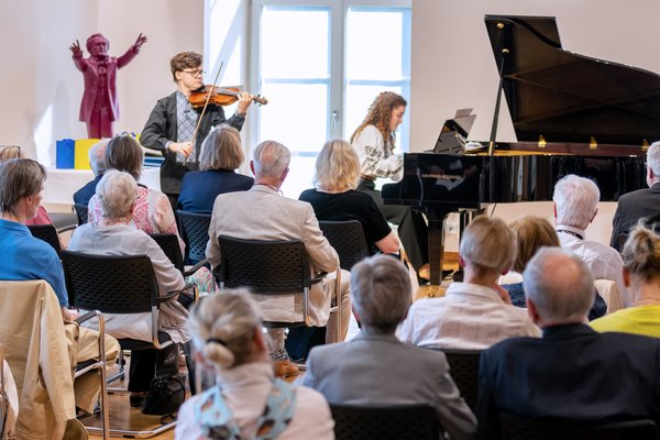 Ein Violinist und eine Pianistin spielen vor Publikum im Leibniz-Saal.