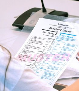Schülerin hält einen Musterstimmzettel in der Hand.
