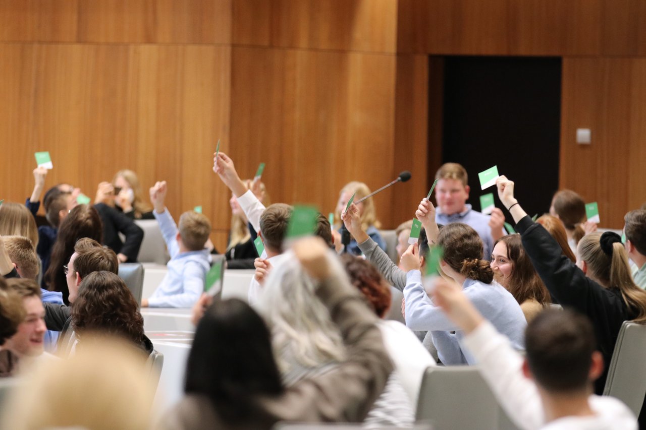 Bild: © Niedersächsischer Landtag Das Publikum hält grüne Kärtchen mit der Aufschrift "pro" in die Luft.