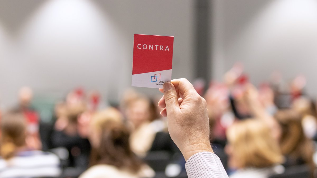 Rote Karten mit er Aufschrift "Contra" werden hochgehalten.