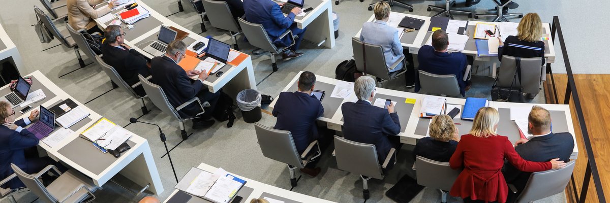 Abgeordnete einer Fraktion sitzen auf ihren Plätzen im Plenarsaal und arbeiten an Unterlagen und Computern.