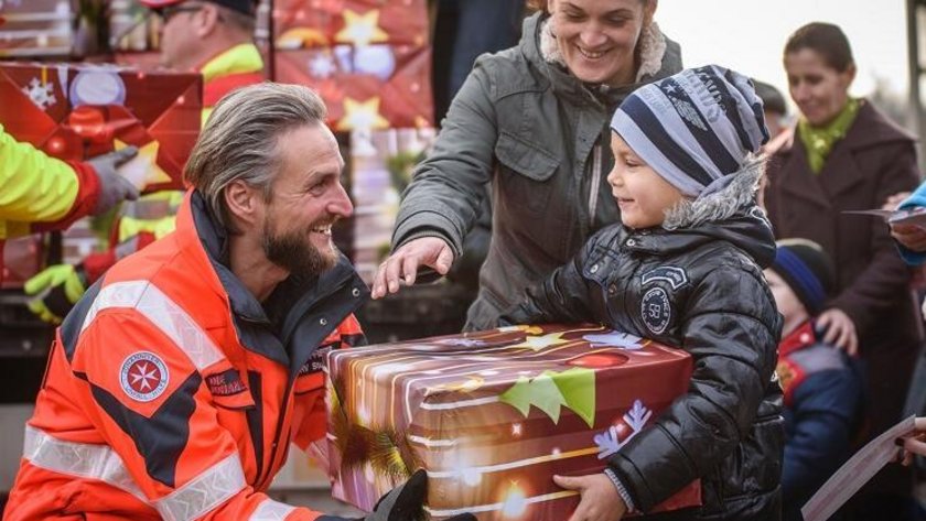 Weihnachtstrucker übergeben Kindern Pakete.
