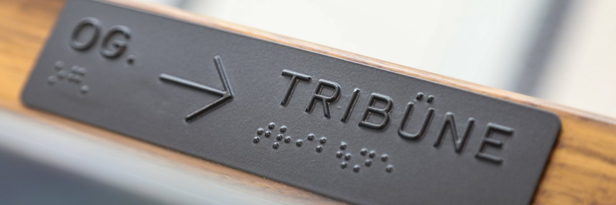 Hinweisschild auf der Tribüne mit Brailleschrift