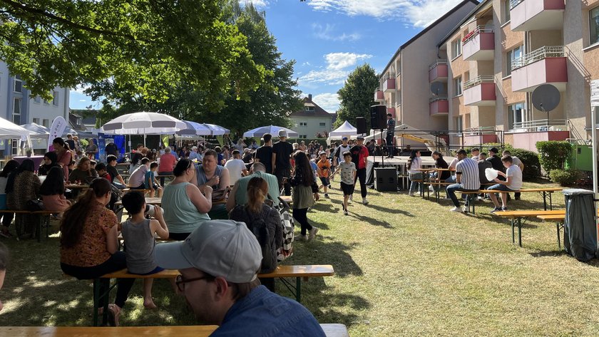 Menschen sitzen im grünen Innenhof zusammen.