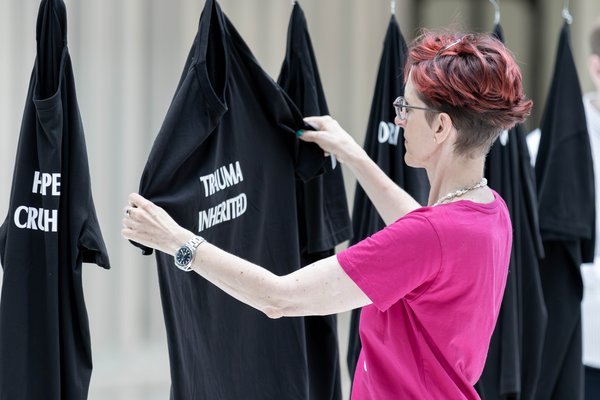 Besucherin sucht sich während der Performance ein passendes Shirt.