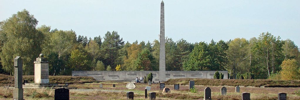 Friedhofsgelände KZ Bergen-Belsen mit Obelisk, Jüdischem Mahnmal, Massengräbern und symbolischen Grabsteinen.