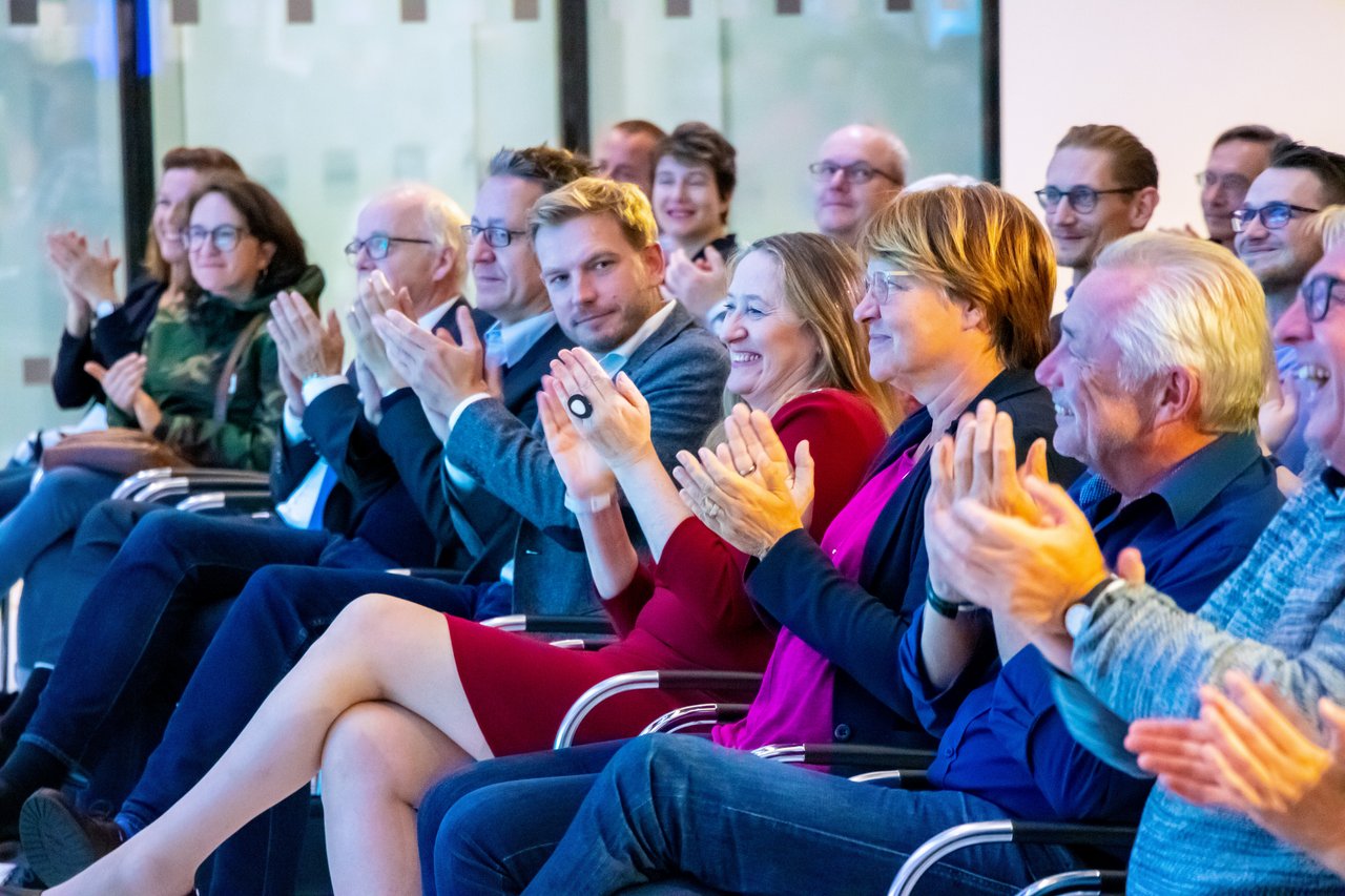 Landtagspräsidentin Andretta sitzt in der ersten Publikumsreihe und lacht.