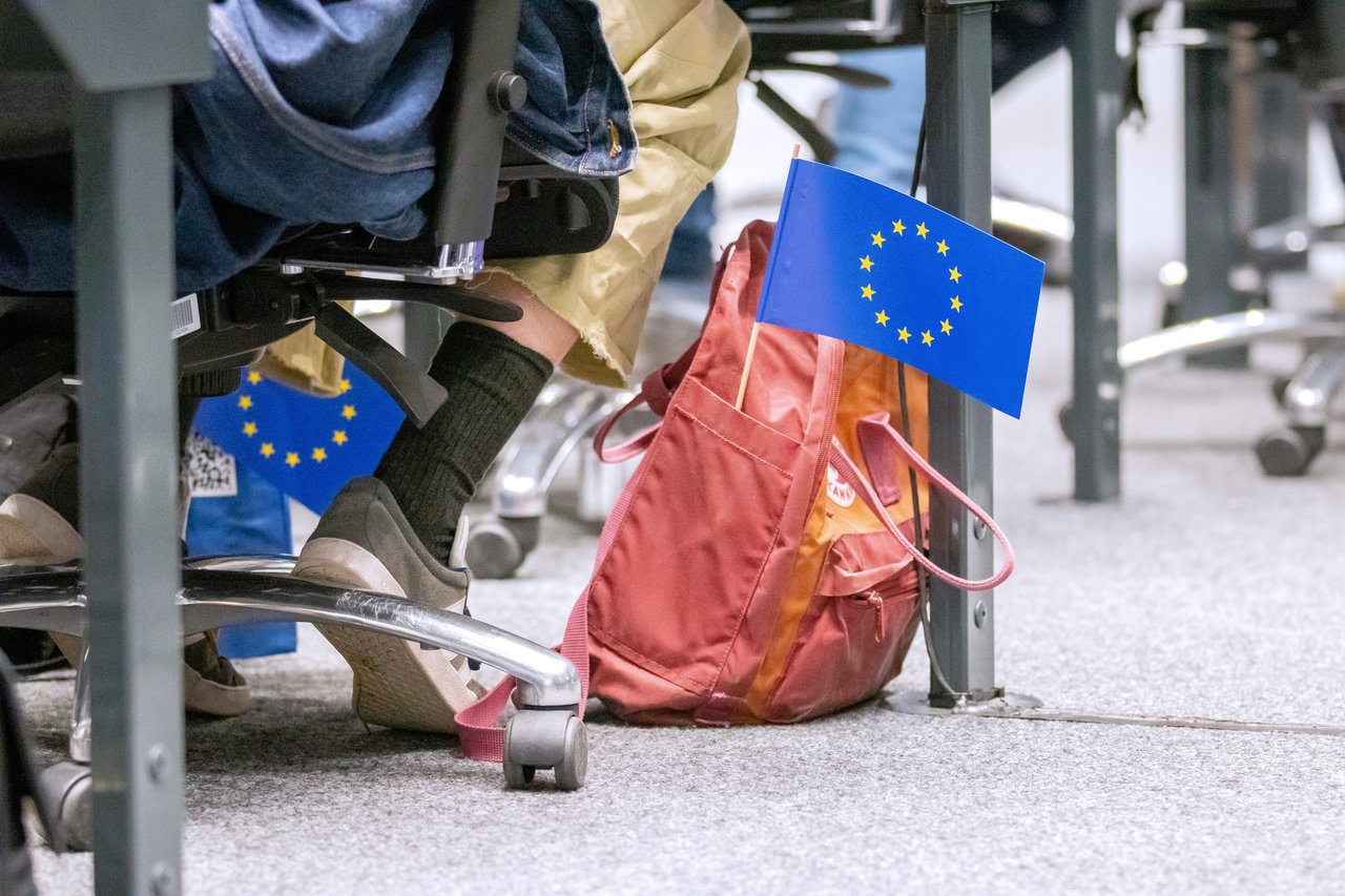 Roter Rucksack auf dem Boden im Forum, heraus ragt eine kleine Europaflagge.