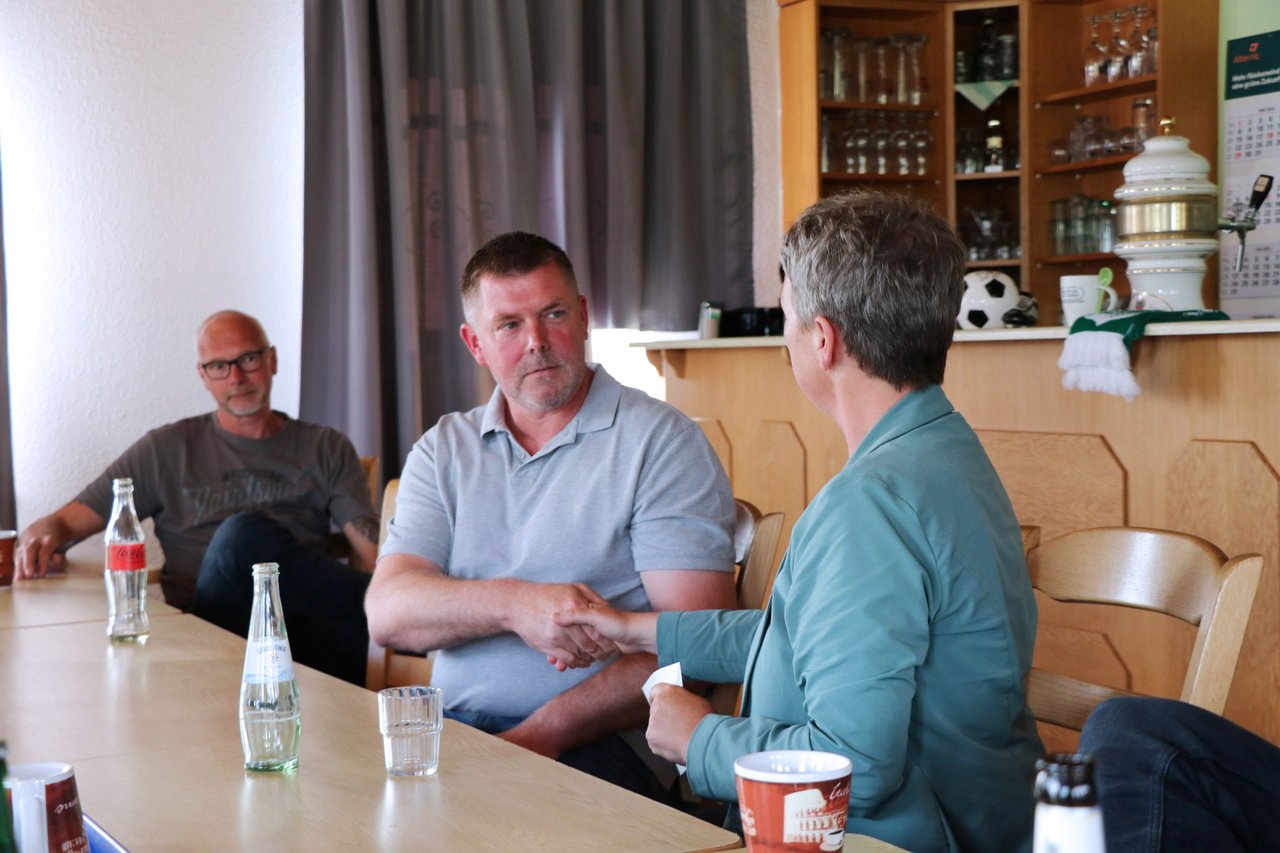 Bild: © Niedersächsischer Landtag Landtagspräsidentin Naber beim SV Ostfrisia Moordorf e.V. im Gespräch mit einem Mann, sie schütteln sich die Hand.