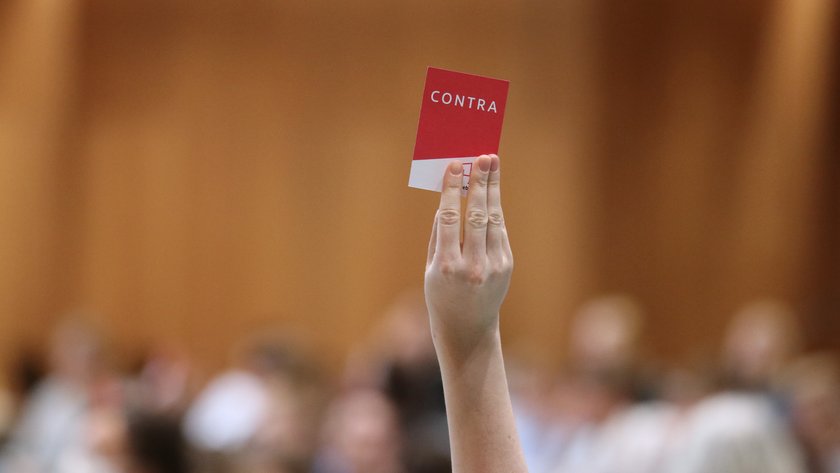Eine rote Karte mit der Aufschrift "contra" wird hochgehalten.