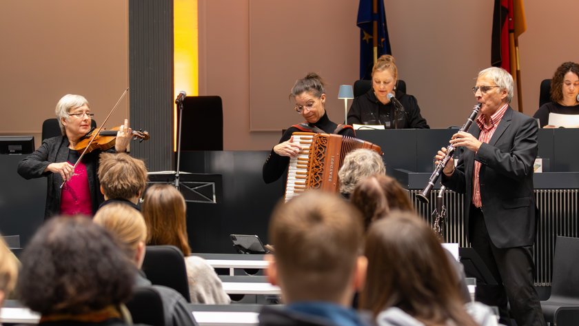 Roswitha Dasch und das Finkelstein Trio musizieren vor einem Publikum aus Schülerinnen und Schülern.