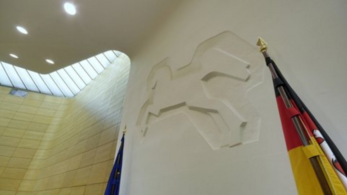 Click opens a magnified version in an overlay. Click ESC to close the overlay. Column at the front of plenary hall with the Saxon steed relief by Professor Kurt Schwerdtfeger, framed by the European and Lower Saxony flags.