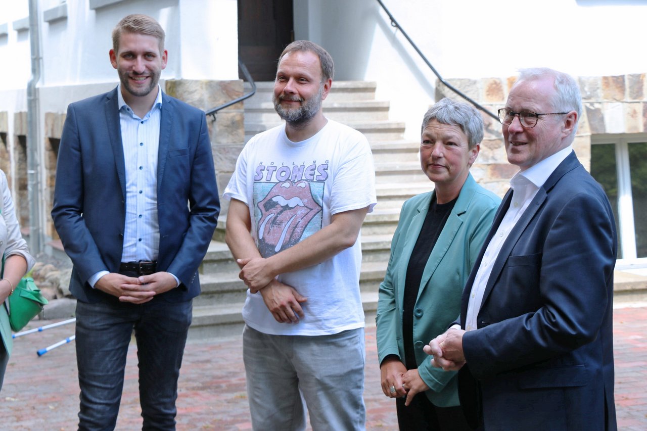 Landtagspräsidentin Naber und drei Männer stehen draußen, alle schauen nach links.