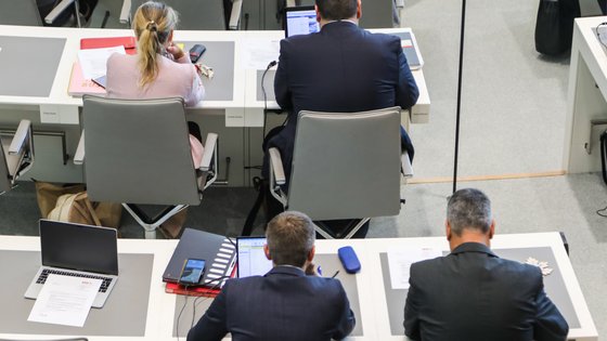 Abgeordnete sitzen an ihren Tischen im Plenarsaal.