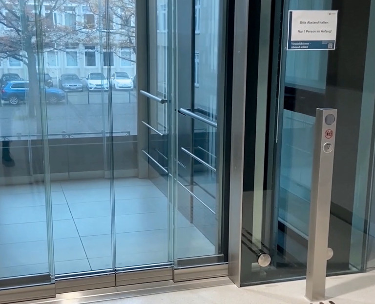 Gläserner Aufzug in der Eingangshalle mit Blick nach draußen auf die Straße.