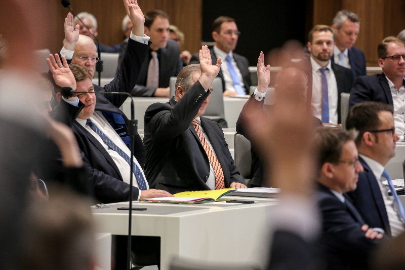 Abgeordnete heben im Plenarsaal die Hände zur Abstimmung.